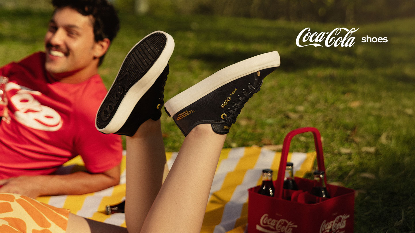 Tênis e Chinelos Coca-Cola sobre um fundo vermelho.