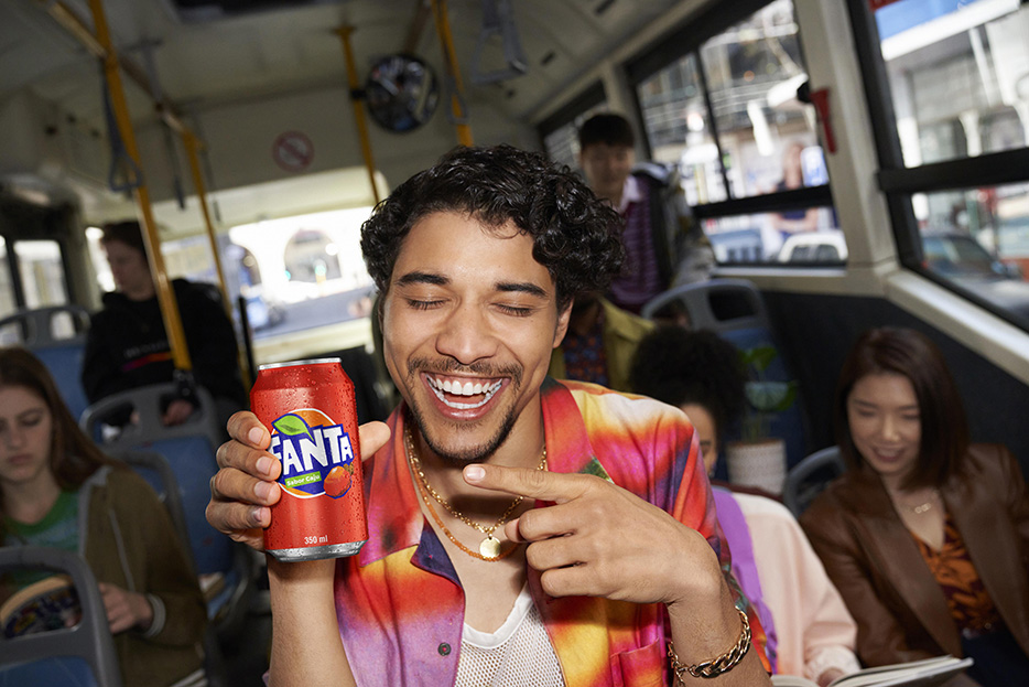 Um garoto segurando uma lata de Fanta Caju.