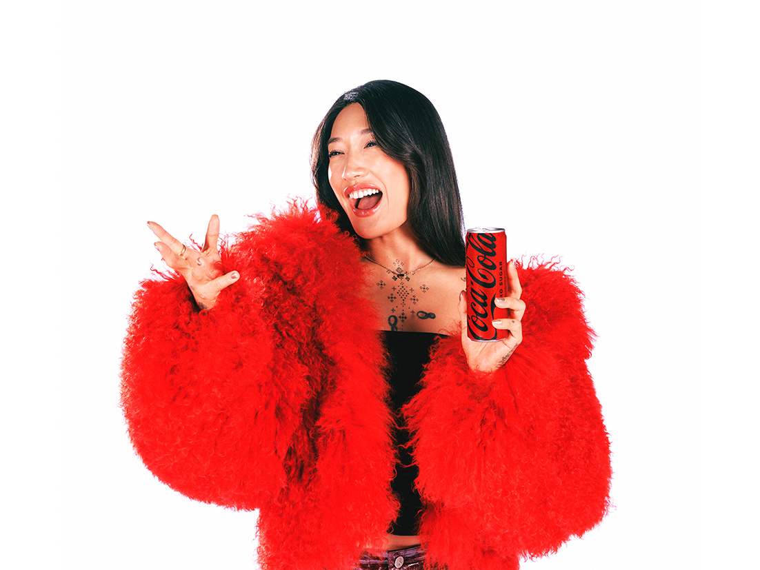 Artista Peggy Gou sorrindo e posando com uma lata de Coca-Cola