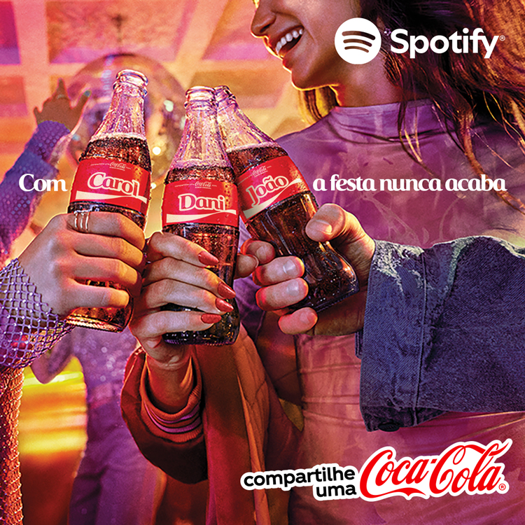 Três pessoas brindando com garrafas de Coca-Cola personalizadas com nomes, em uma festa animada, com o logo do Spotify e o texto "compartilhe uma Coca-Cola" no canto.