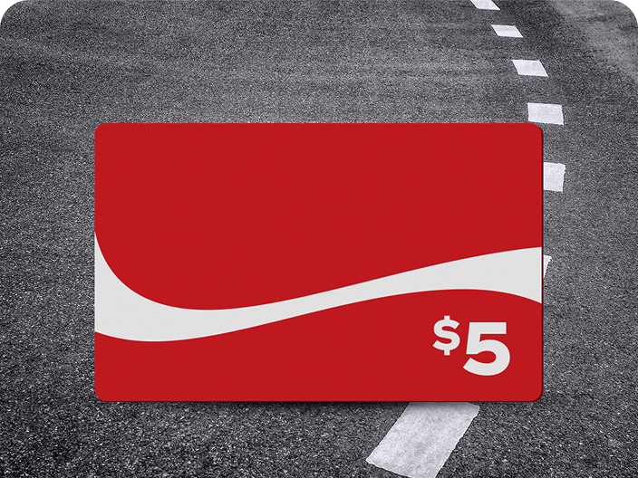 A red $5 prepaid Coca-Cola gift card, a prize for the Road Trip contest, shown on an asphalt road background.