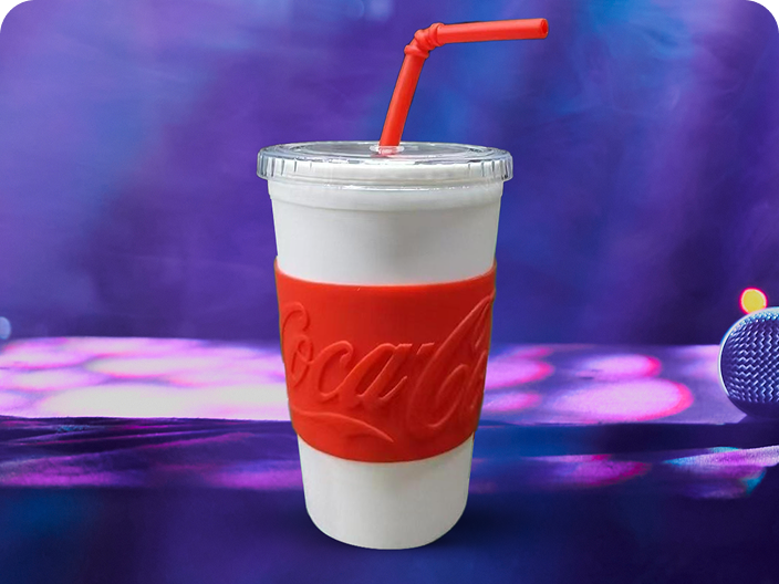 A reusable tumbler with a Coca-Cola branded sleeve, a prize from the Festive Moments pool, shown against a purple background.