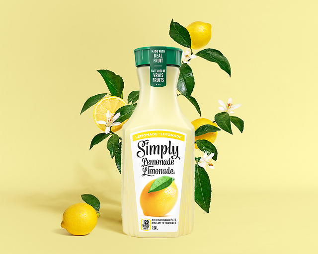 a carafe of simply lemonade on a leafy yellow background