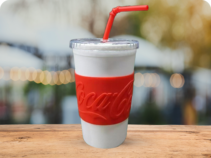 Un gobelet réutilisable blanc avec un manchon rouge texturé de marque Coca-Cola et une paille rouge, un prix du concours d'été.