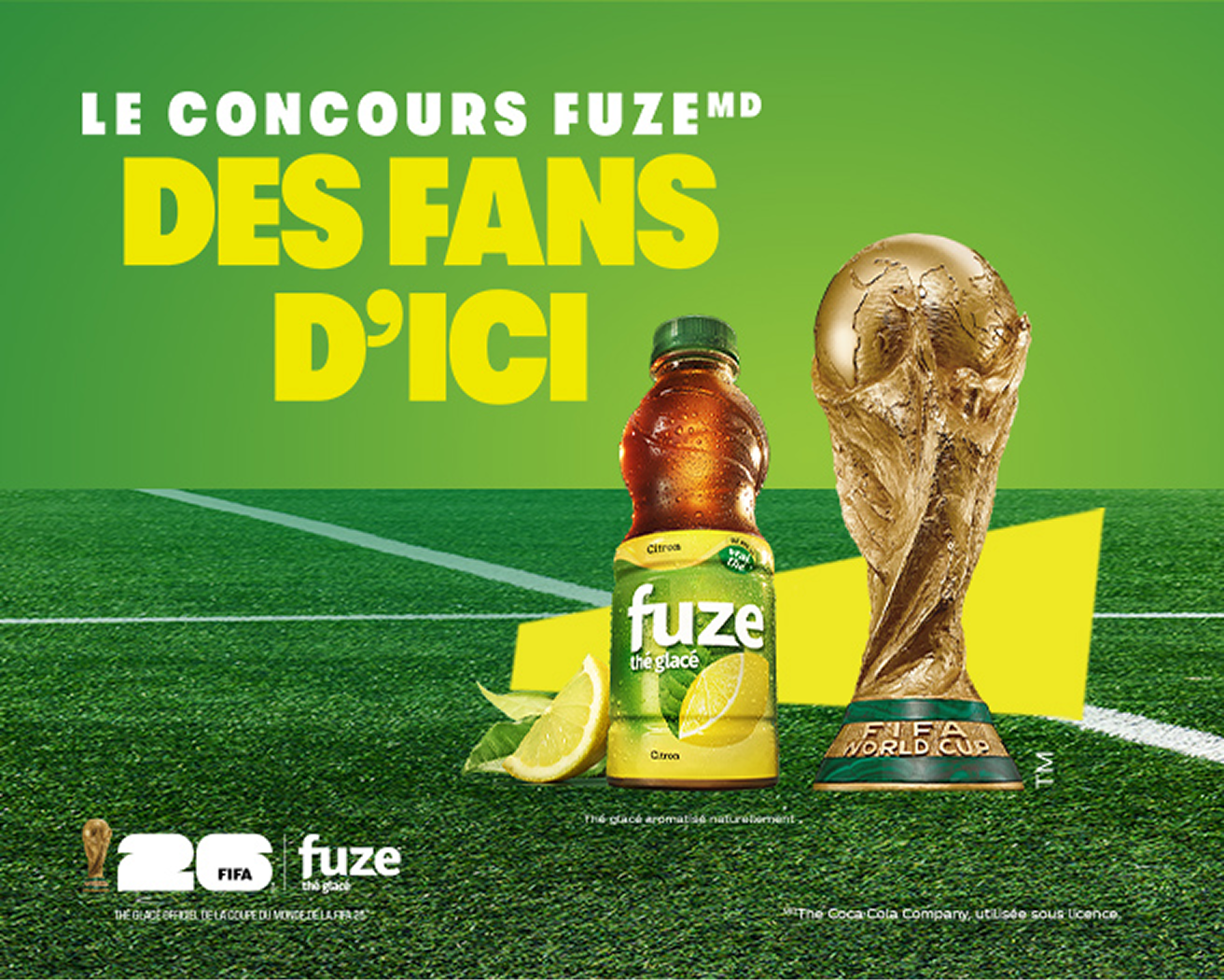Bouteille de thé glacé FUZE🅫 citron à côté du trophée doré de la Coupe du Monde de la FIFA sur un terrain de soccer, concours pour chaque fan