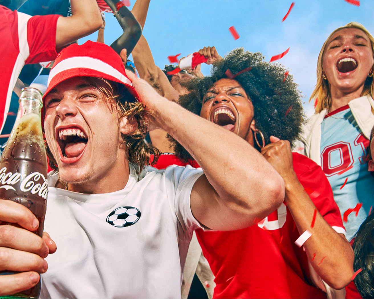 Groupe de fans de soccer qui acclament en tenant une bouteille de Coca-Cola en verre