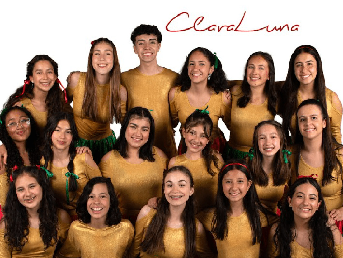 Foto grupal de jóvenes del grupo musical ClaraLuna, con trajes dorados y verdes, sonrientes y posando para la cámara bajo un fondo blanco.