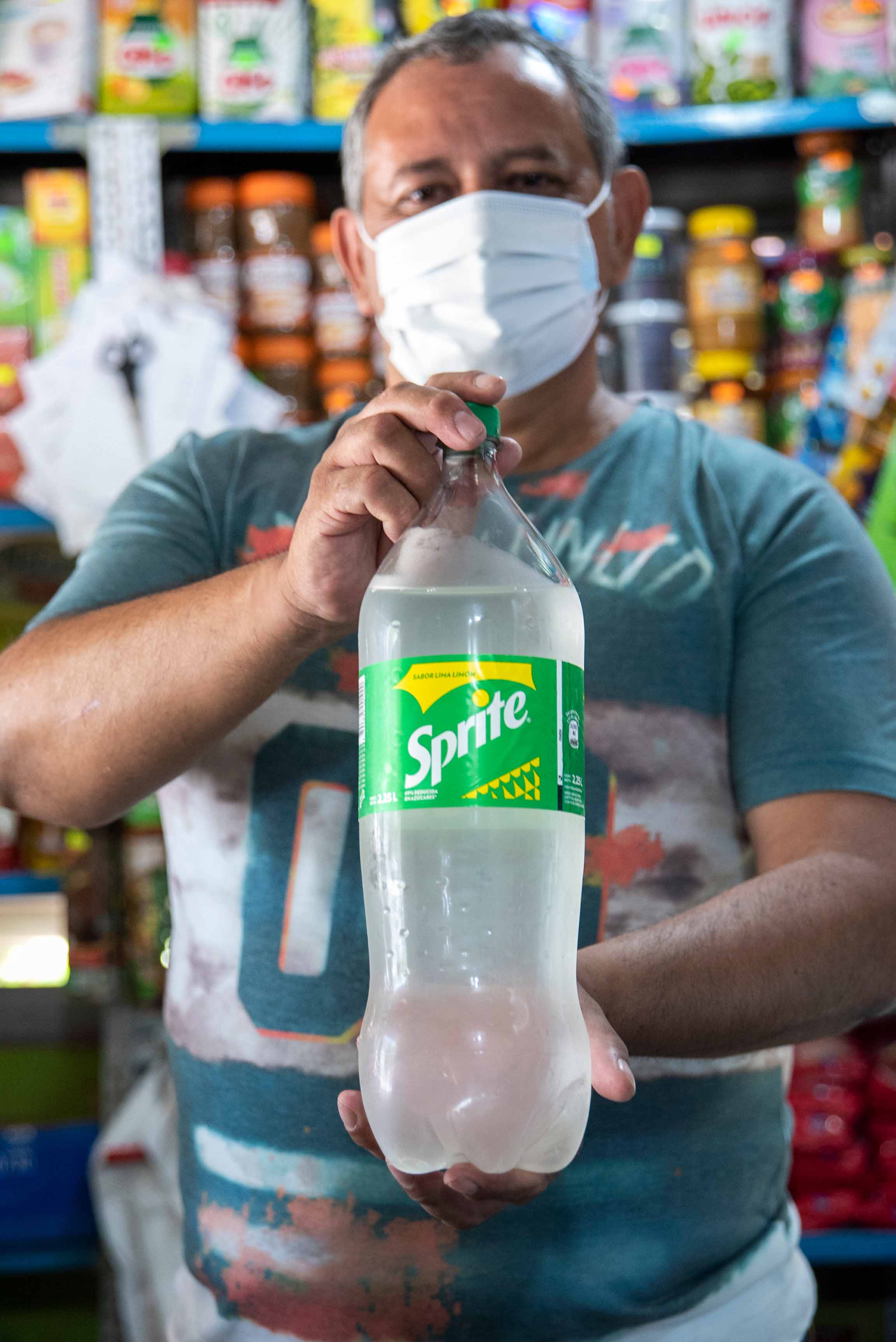 Un hombre sostiene una botella de Sprite