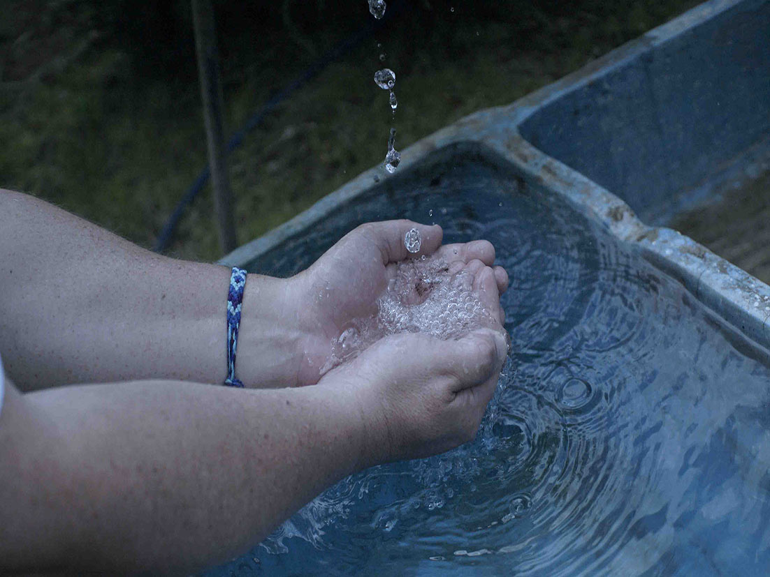 Gotas de agua se deslizan sobre dos manos