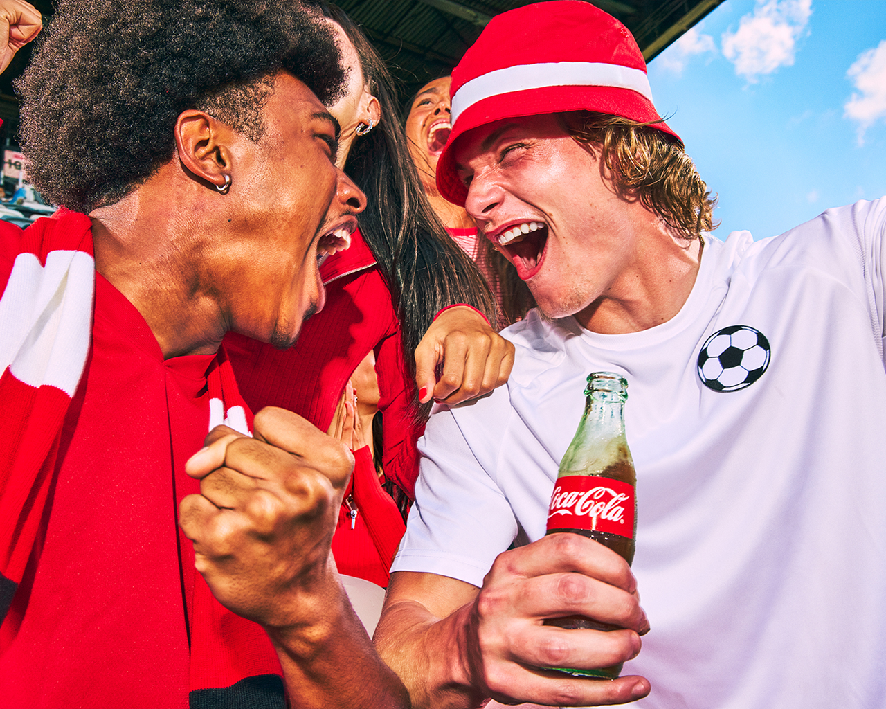 Fodboldfans jubler og holder en Coca-Cola glasflaske