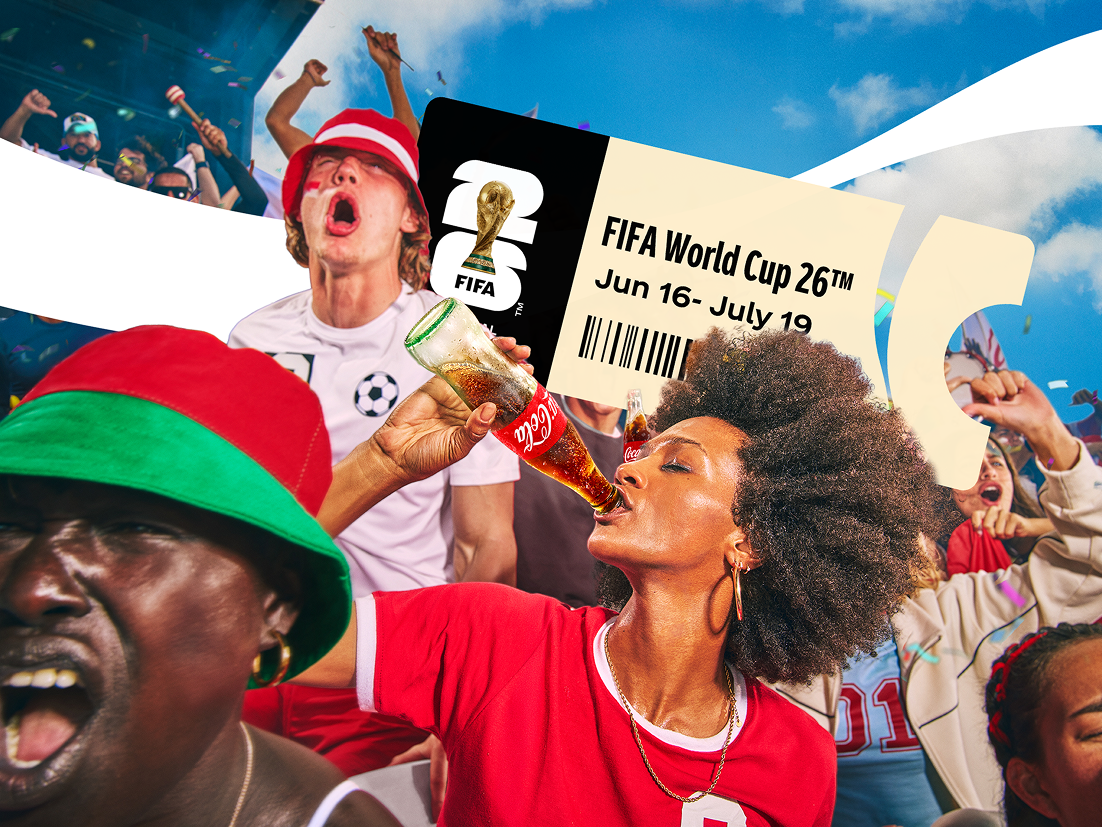 Groep voetbalsupporters in rood‑groene kleding viert uitbundig feest; één persoon drinkt uit een Coca‑Cola‑fles terwijl anderen juichen en een bord omhooghouden, tegen een heldere blauwe achtergrond.