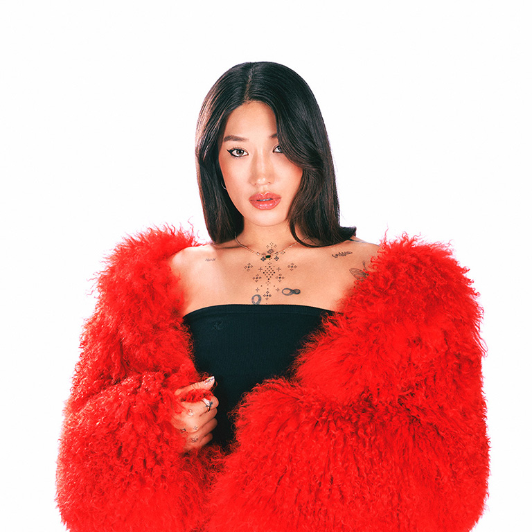 Peggy Gou, vistiendo una chaqueta de piel roja, en un fondo blanco.