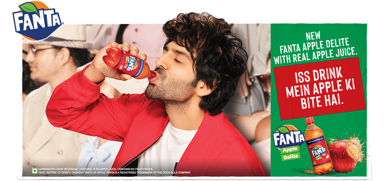 Young man enjoying a Fanta Apple Delite in a crowd with the words: NEW FANTA APPLE DELITE WITH REAL APPLE JUICE. ISS DRINK MEIN APPLE KI BITE HAI.