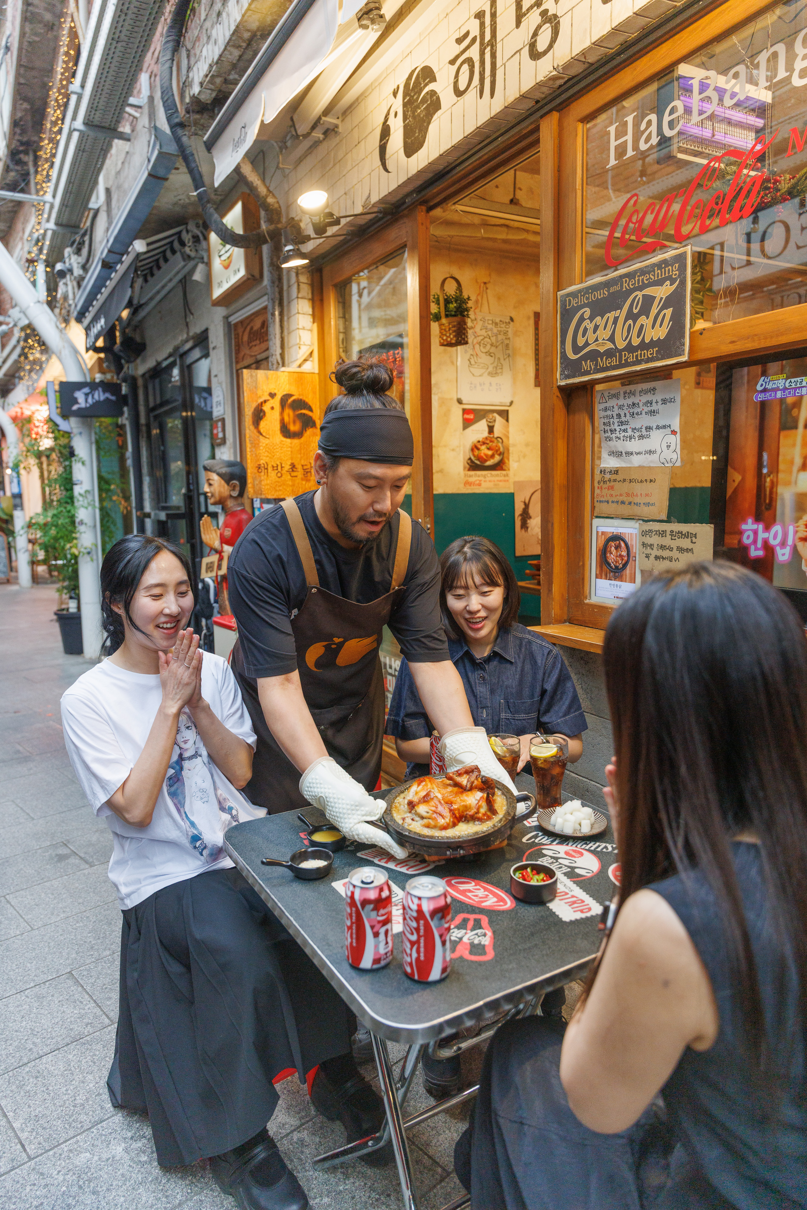 신흥시장에 위치한 전기구이 통닭집, 해방촌닭의 야외 좌석에서 손님들에게 음식을 서빙하고 있는 류호 사장의 모습