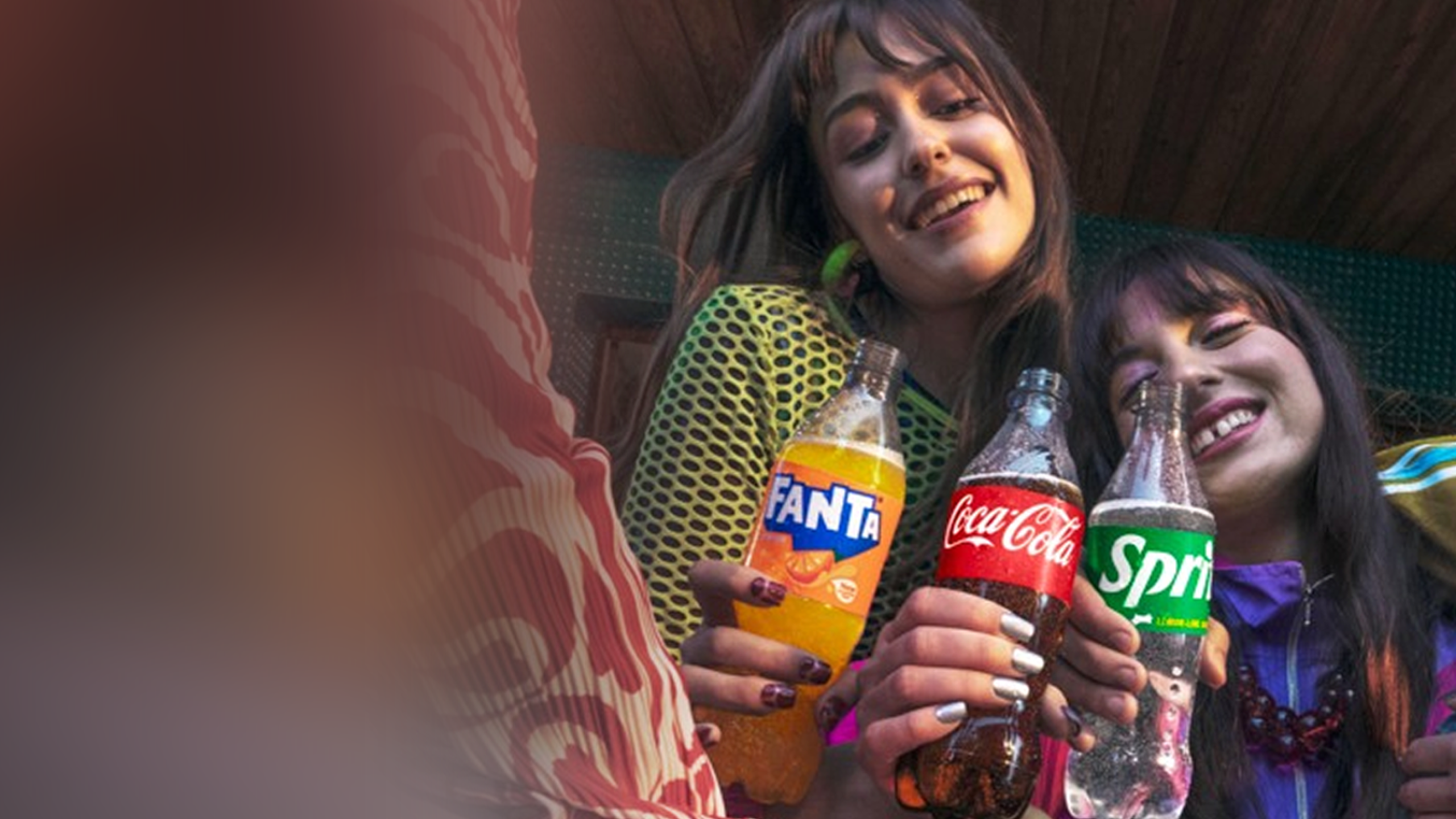 Mai multe persoane ciocnesc doze de Fanta, Coca‑Cola și Sprite.