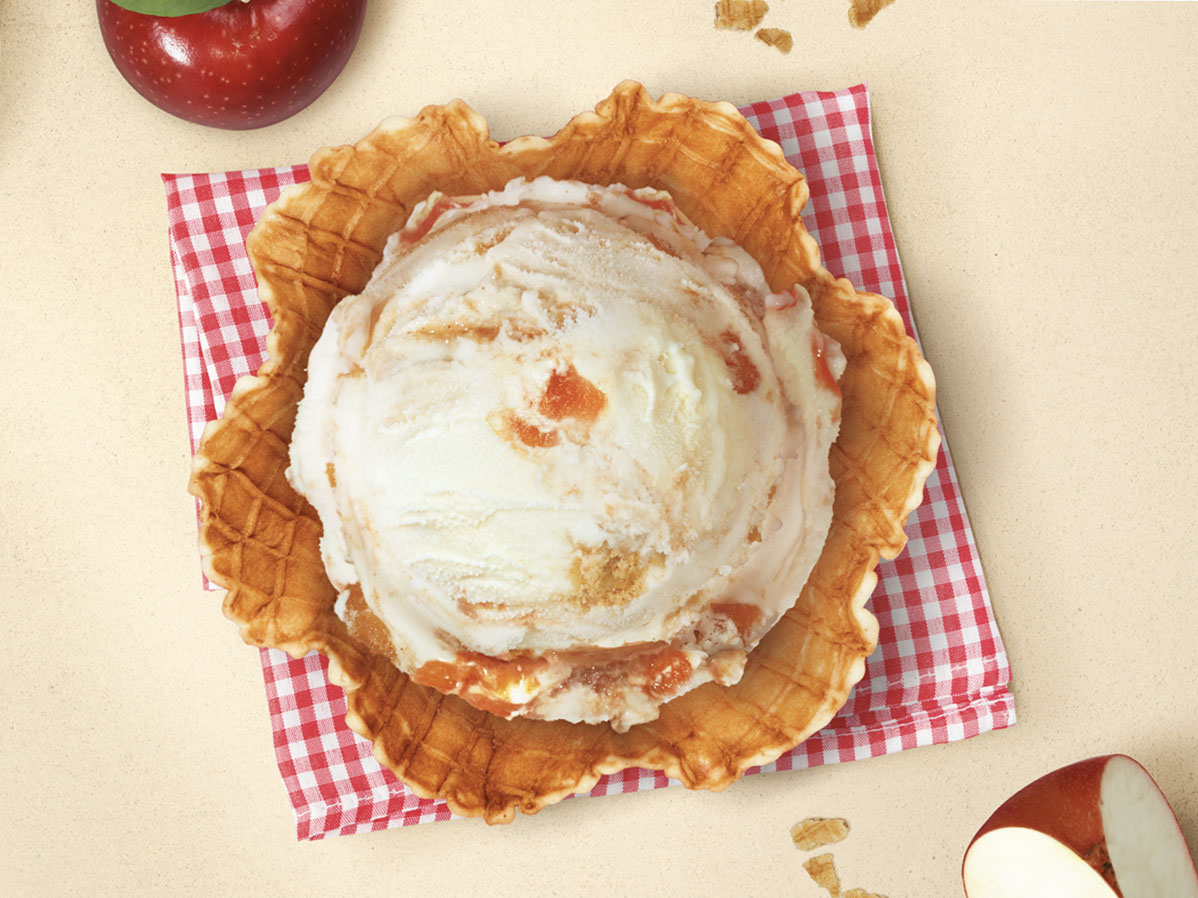 Helado de strudel de manzana de Santa Clara Mexico en una cesta de barquillo, con manzanas rojas y migas de strudel de fondo.