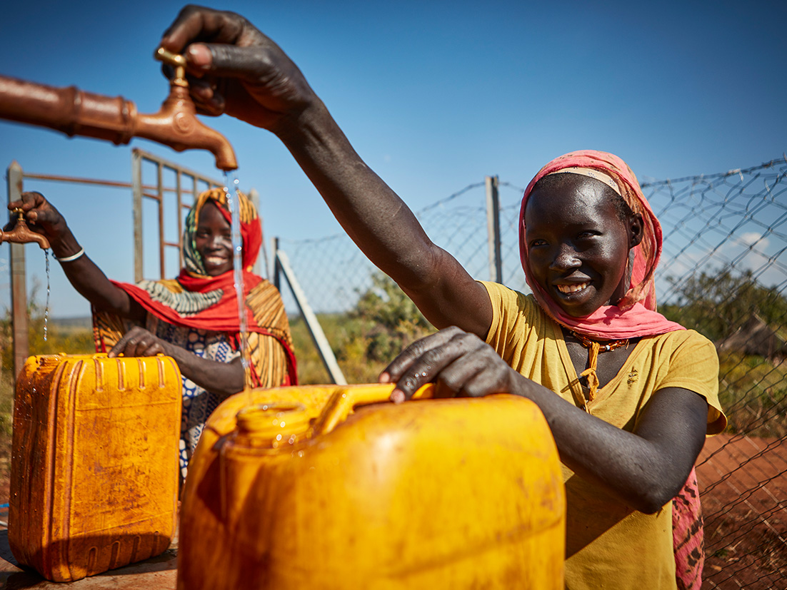 Children smiling while filling gallons with water