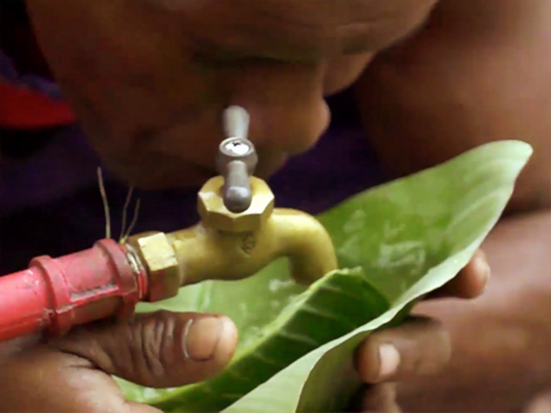 Man drinking water directly from a tap with a leaf