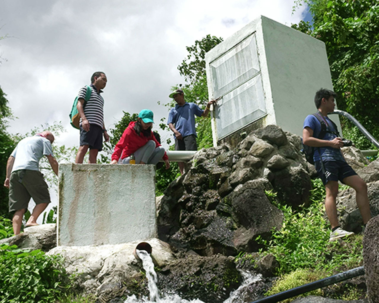 People on a acclivity next to water pipes