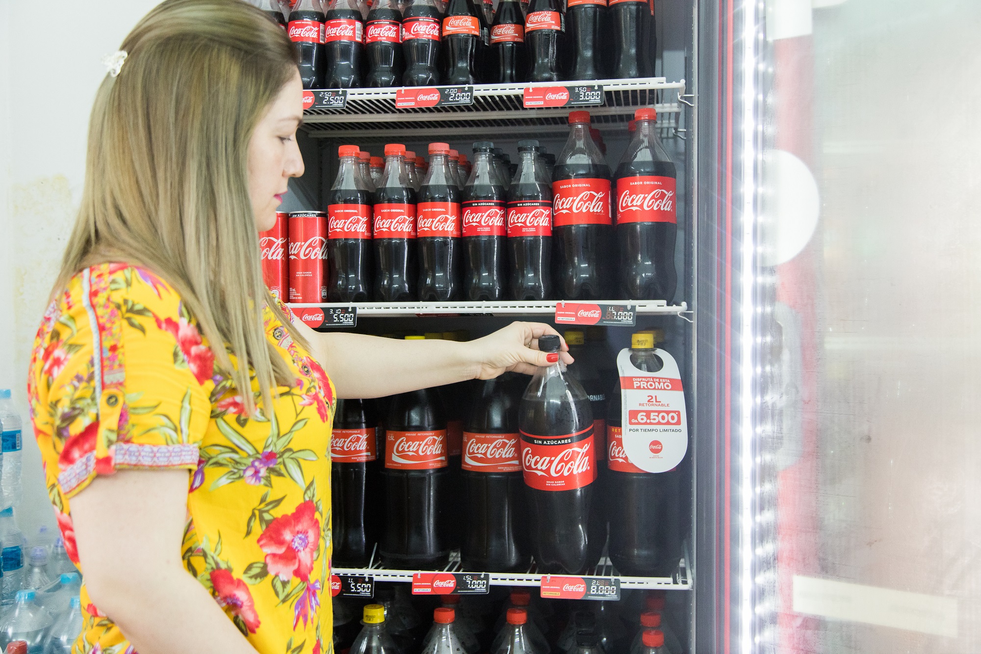 Mujer tomando una Coca-Cola de la nevera