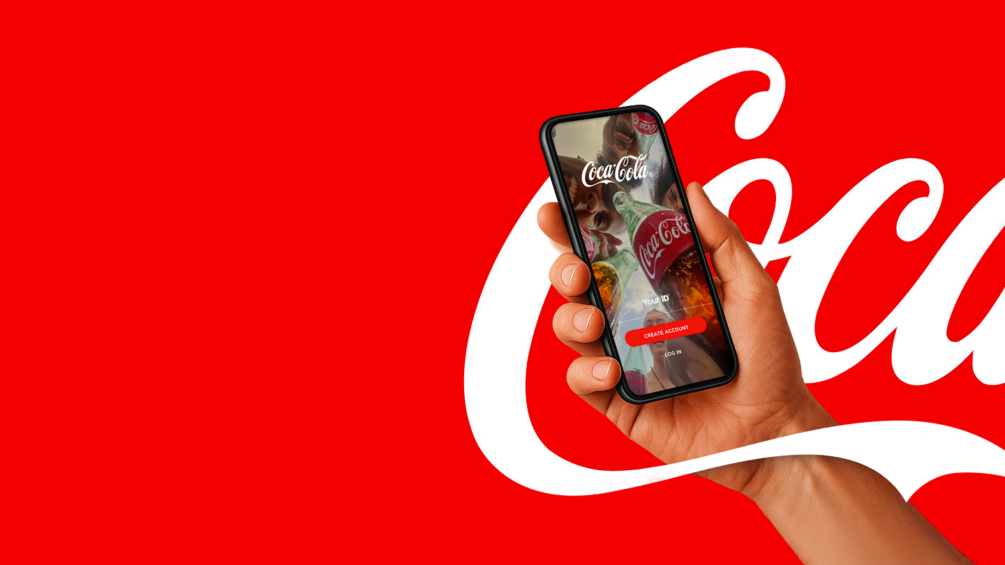 Ruka drži pametni telefon sa aplikacijom Coca‑Cola na crvenoj pozadini