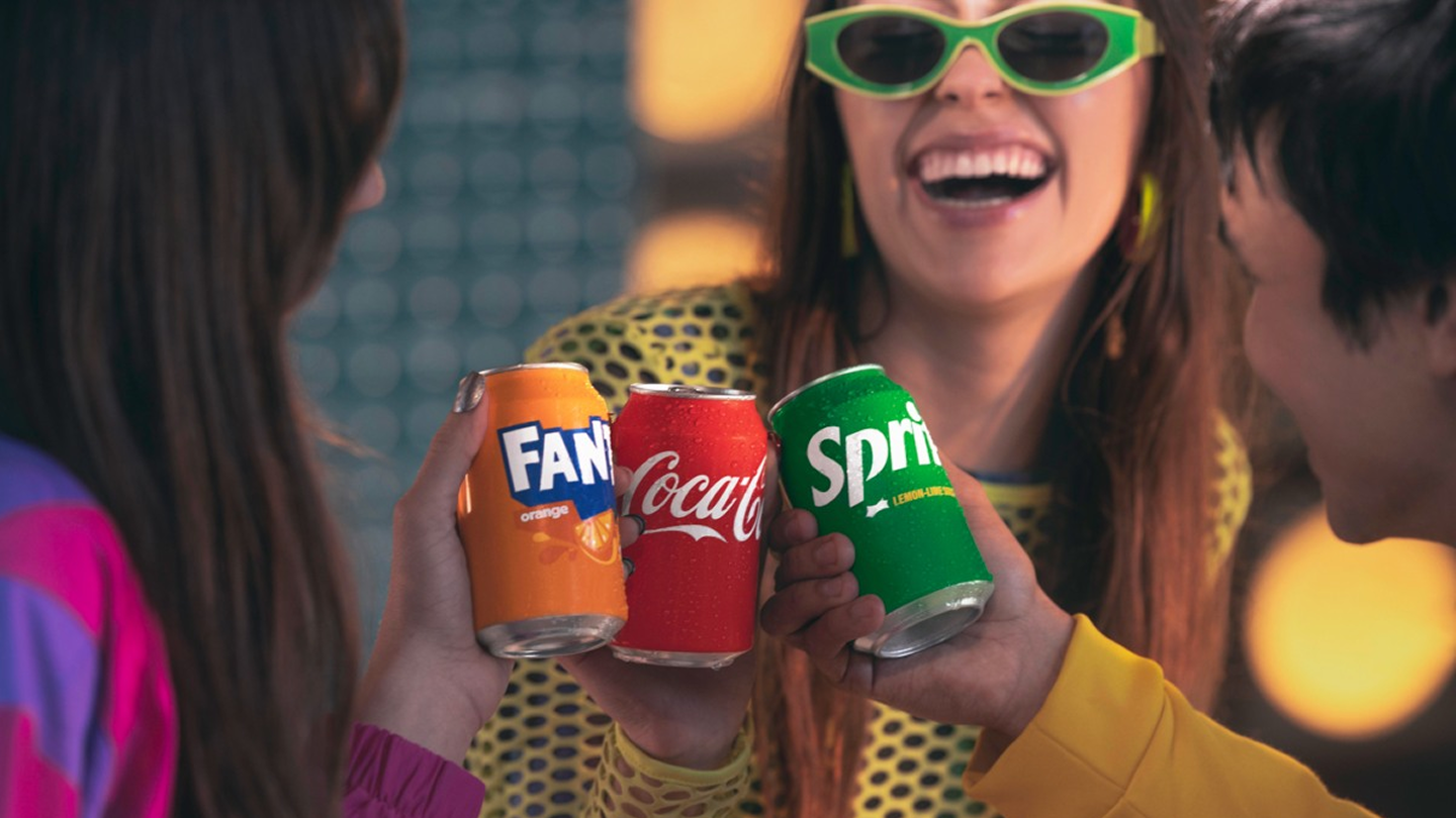 Nekoliko osoba kucka se limenkama Fante, Coca‑Cole i Spritea.