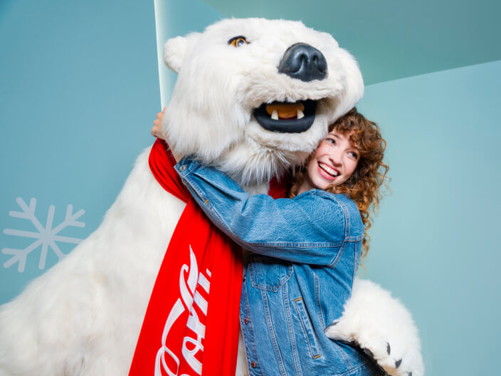 person in denim hugging coca cola polar bear