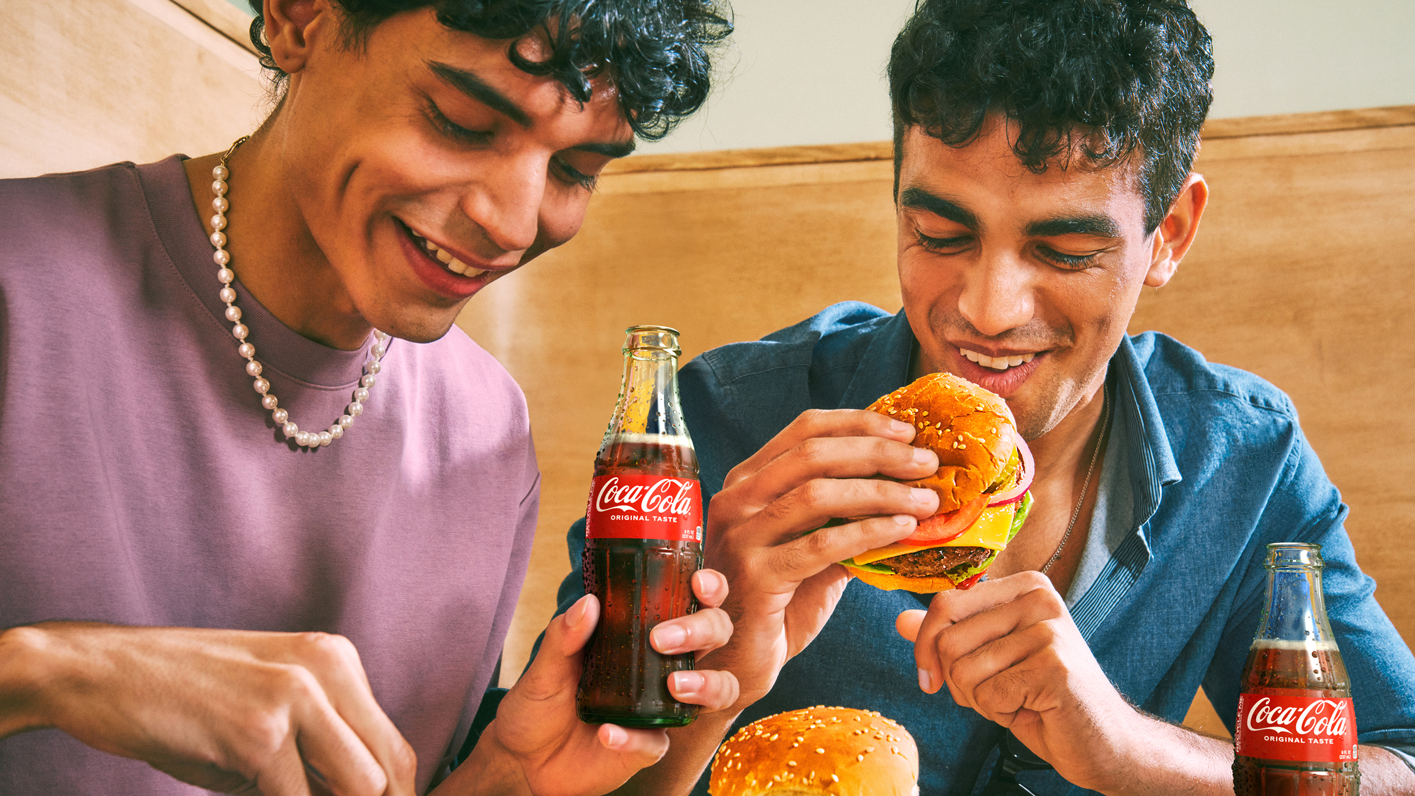 two friends eating burgers with coca-cola