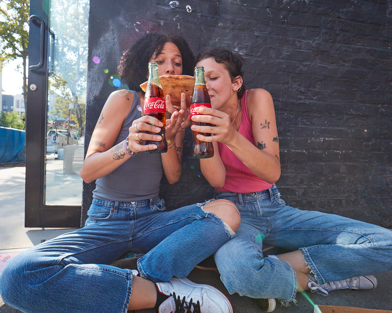 two friends sharing pizza and coca-cola