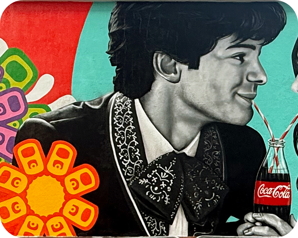 Close-up of a man in a charro suit sharing a Coca‑Cola in the Paint the Nation mural by Los Otros.