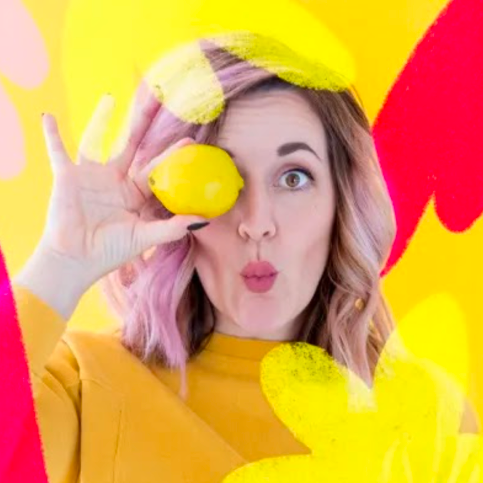Artist with pastel purple hair in a yellow top posing against bold yellow and pink painted shapes, highlighting the bright style of the Paint the Nation murals.