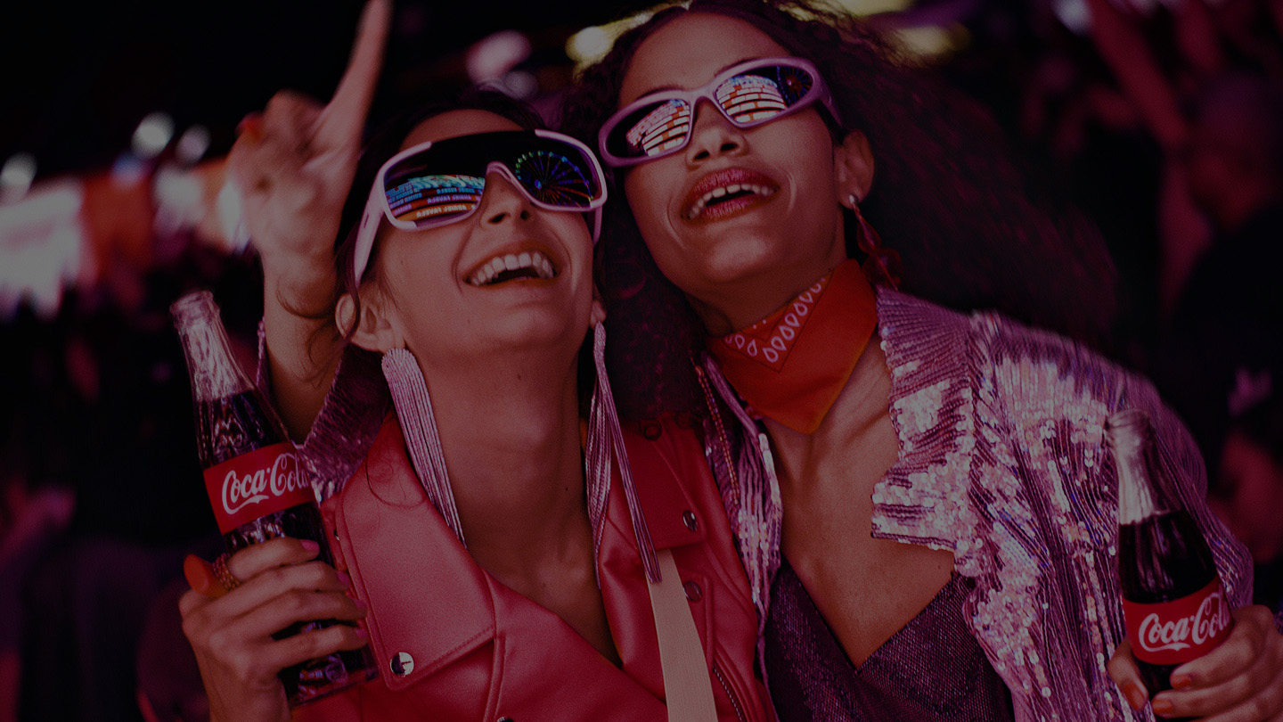 two people holding Coca-Cola at a music festival