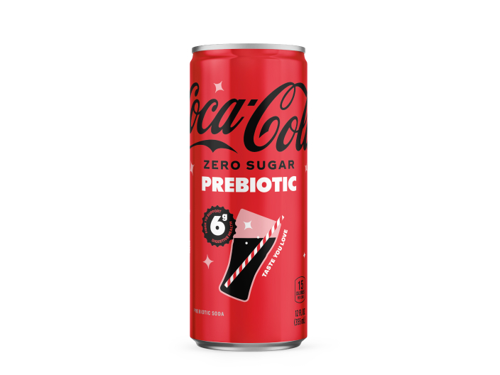 A red can of Coca-Cola Zero Sugar Prebiotic soda against a white background, featuring a "6g fiber to support digestive health" badge, a glass-and-straw graphic, "Taste You Love" text, and product details noting 15 calories per can and 12 FL OZ (355 mL).