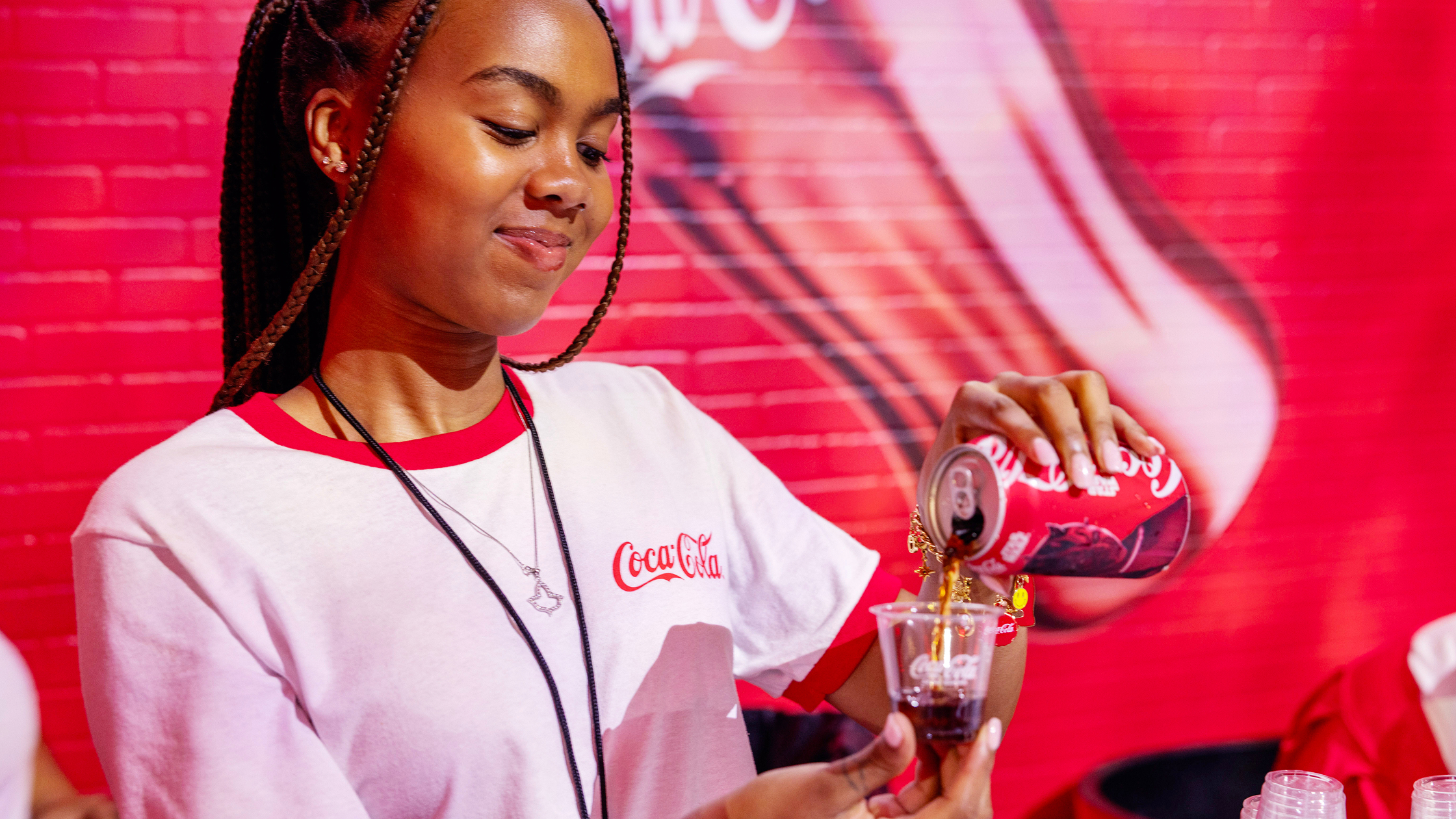 An HBCU student smiles while holding a Coca-Cola bottle at ESSENCE Festival