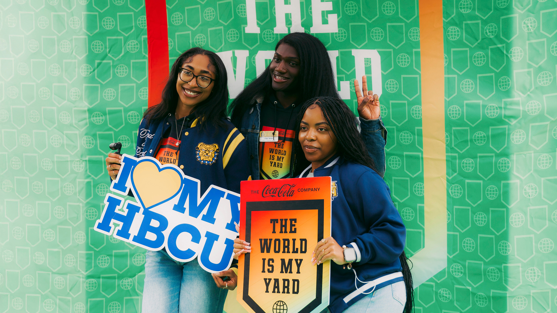 A group of HBCU students posing together with Coca-Cola branded signage at a The World Is My Yard activation