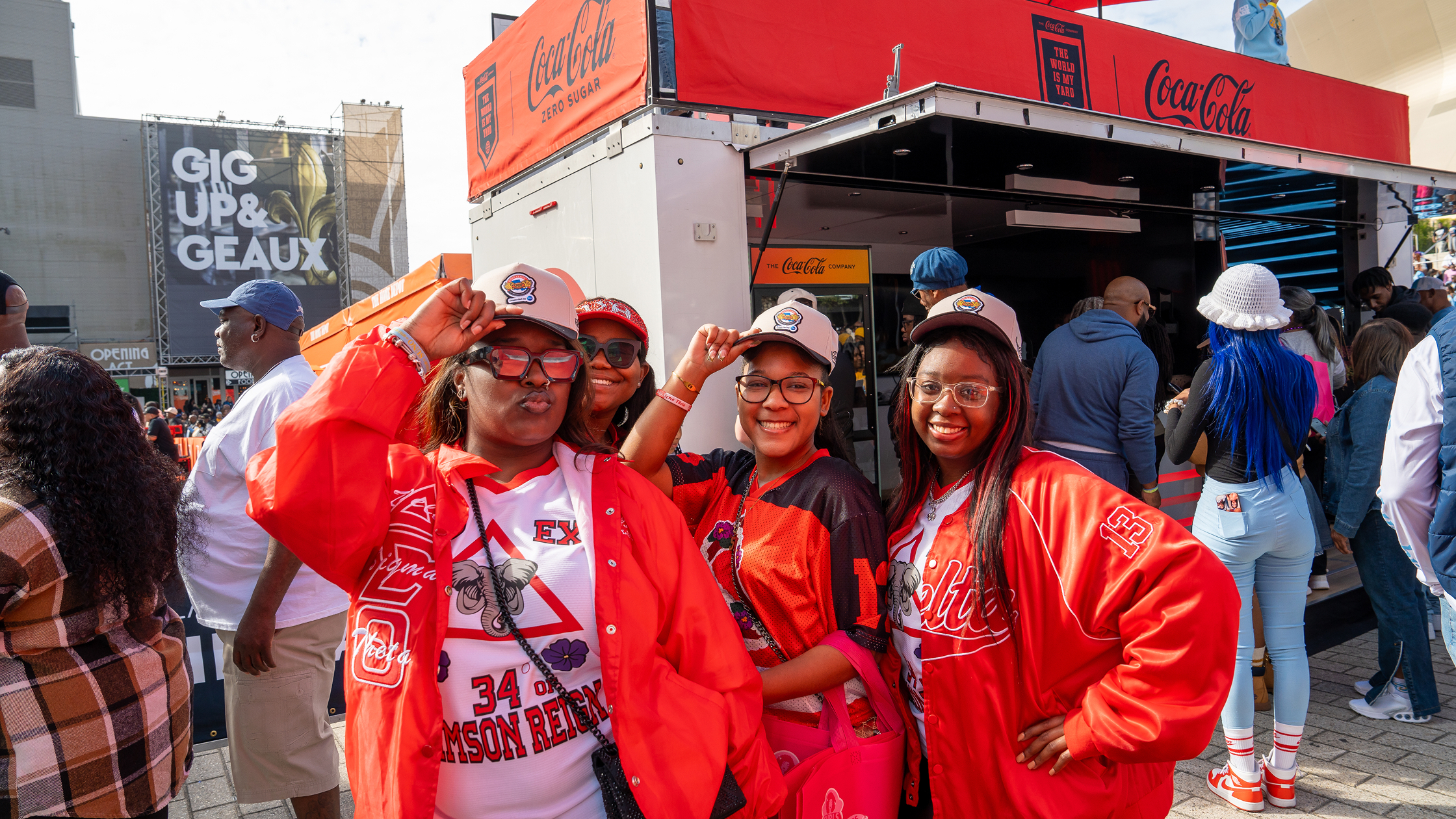 A group of HBCU students posing together with Coca-Cola branded signage at a The World Is My Yard football game activation