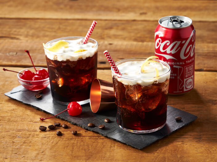 two cola cocktails with cherry and a can of coca cola