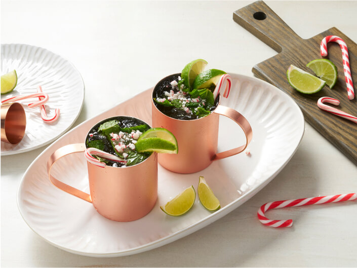 two moscow mule type drinks on a plate with limes