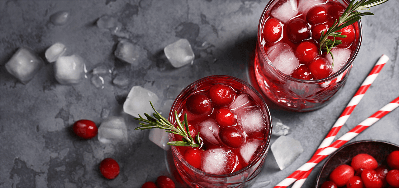 an aerial view of two red drinks with garnish, ice, and cranberries