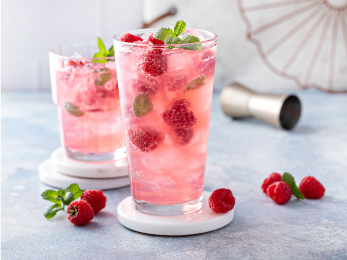 two pink drinks with raspberries